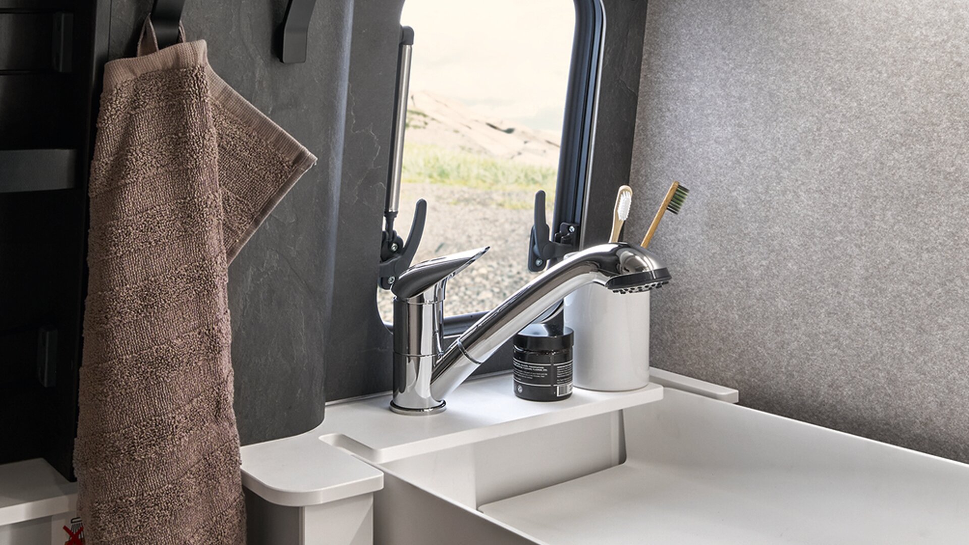 Il lavandino del HYMER Grand Canyon S in posizione abbassata è visibile con rubinetto incluso. Accanto c'è appeso un asciugamano.