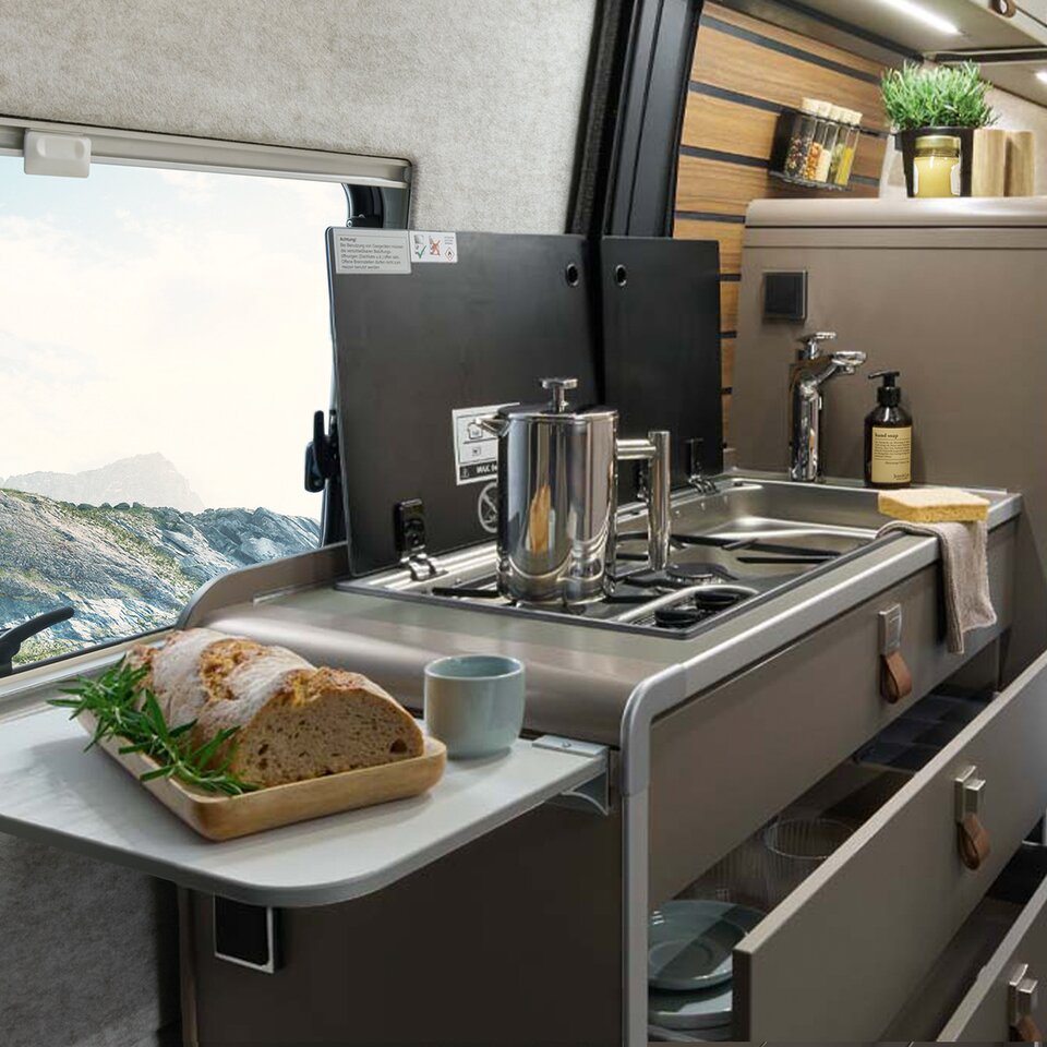 Auf der Küchenerweiterung im HYMER Grand Canyon S liegt Brot. Im Hintergrund liegt die Küchenzeile mit Herd, Spüle und Kühlschrank.