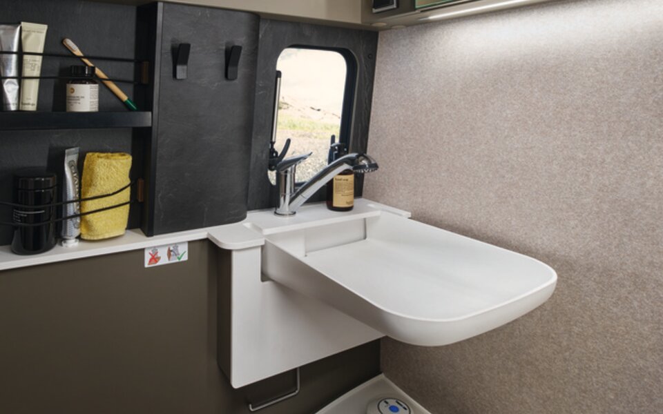 Dans la salle de bains compacte du HYMER Grand Canyon S dans le monde du style Ivy Green, il existe de nombreuses options de rangement pour vos articles de toilette.