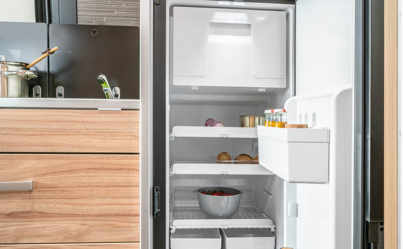 Open en volle koelkast geïntegreerd in het keukenblok, laden, planken, bovenkasten in de HYMER Grand Canyon S