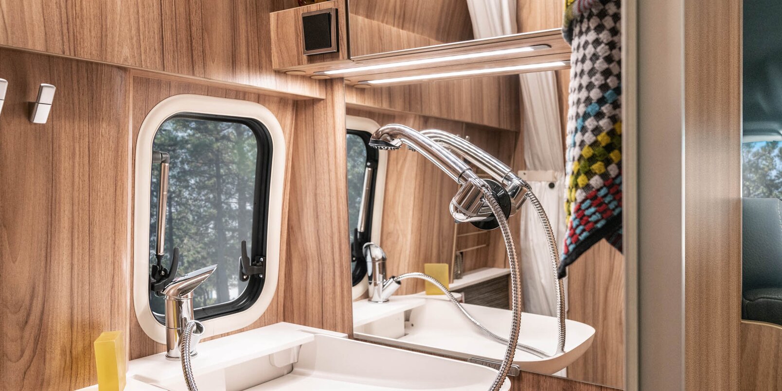 Lavandino con doccetta, specchio, asciugamano e finestra nel Mercedes-Sprinter Grand Canyon S HYMER