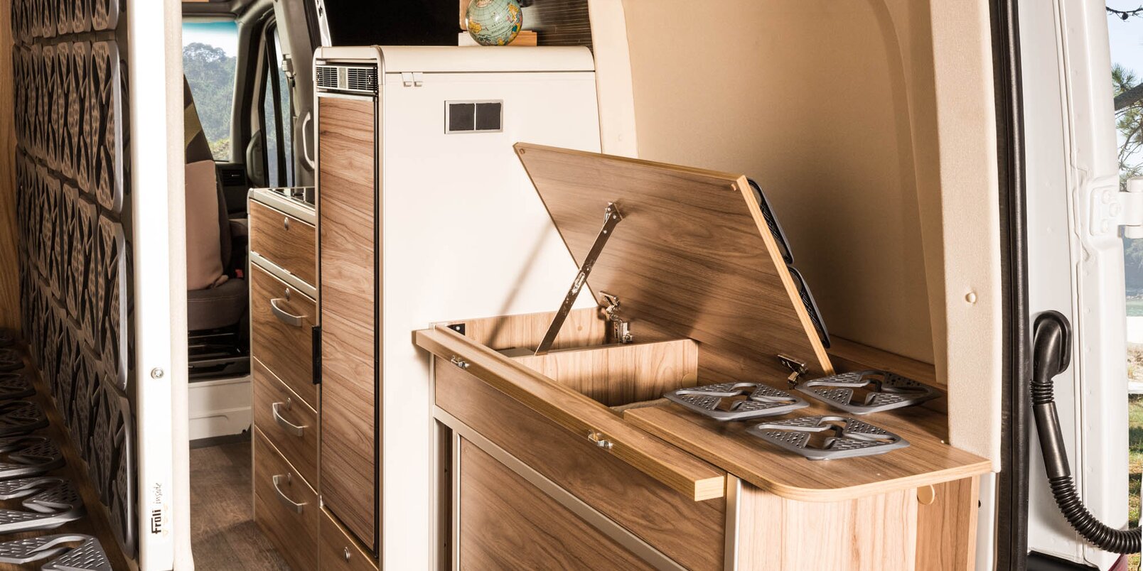 Open storage compartment under the bed, folded bed frame, refrigerator, kitchen block in the HYMER Grand Canyon S