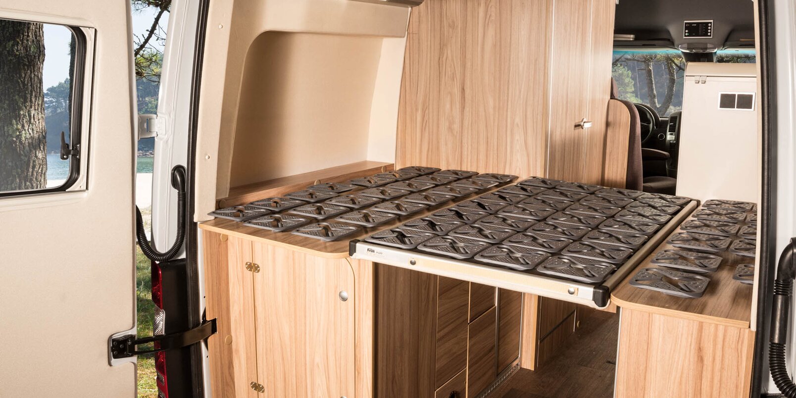 Rear area in the HYMER Grand Canyon S: Lounger area with plate spring frame, including storage cupboards, open rear doors