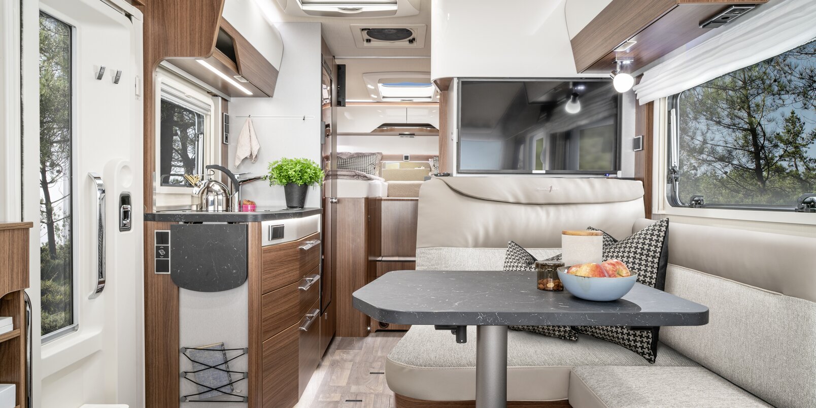 Living room in the HYMER B ModernComfort with seating area including TV plasma, kitchen and sleeping area