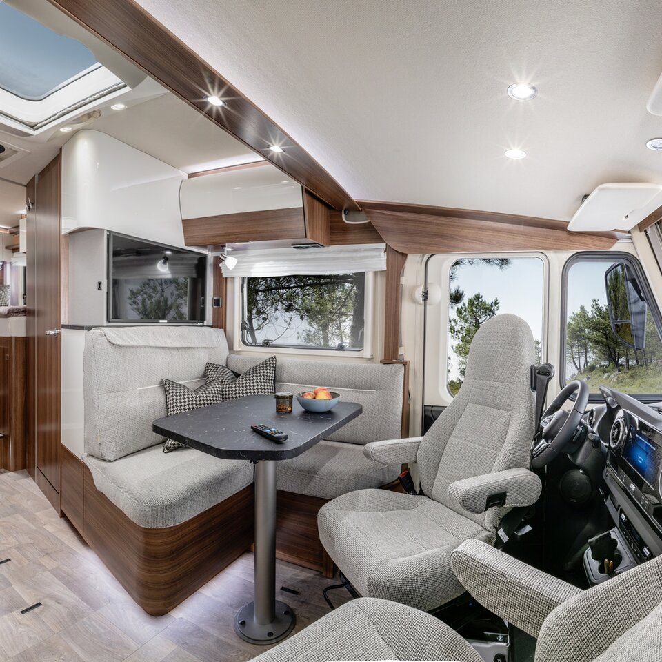 Wohnsitzgruppe mit Fahrersitzen und Dekokissen, TV-Plasma und Küchenblock im HYMER B ModernComfort