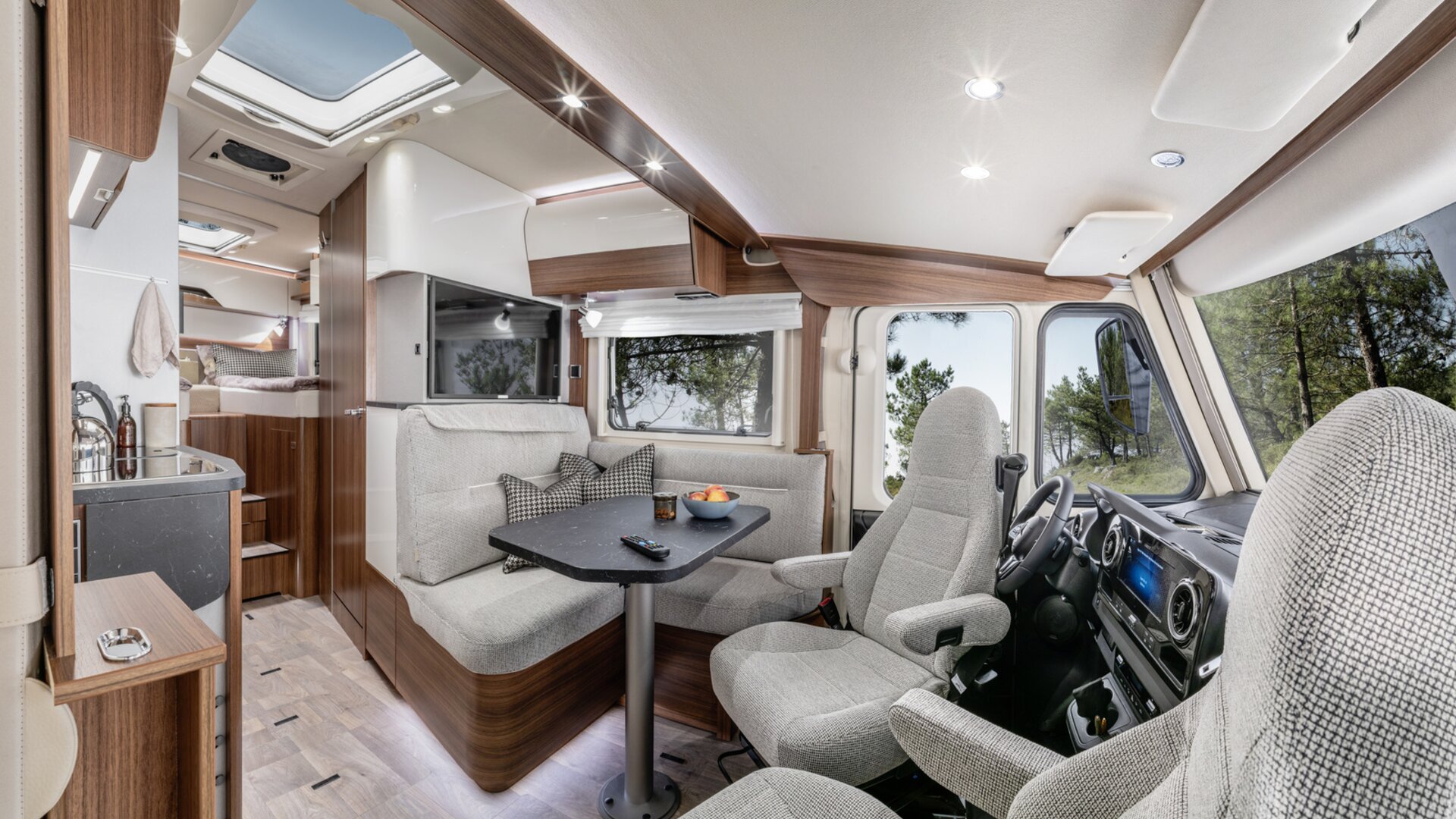 Wohnsitzgruppe mit Fahrersitzen und Dekokissen, TV-Plasma und Küchenblock im HYMER B ModernComfort
