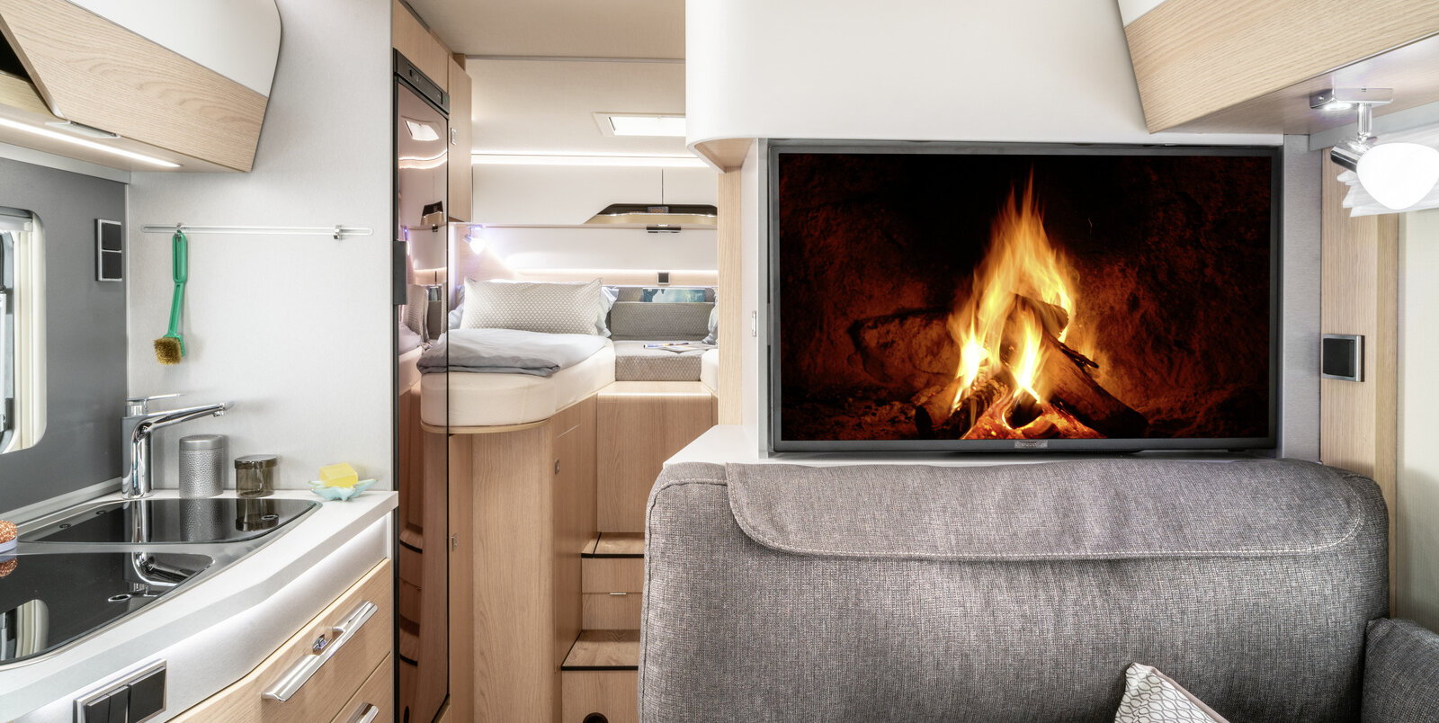 Living room in the HYMER B-MC with seating area and fireplace on the TV plasma, kitchen and rear bed