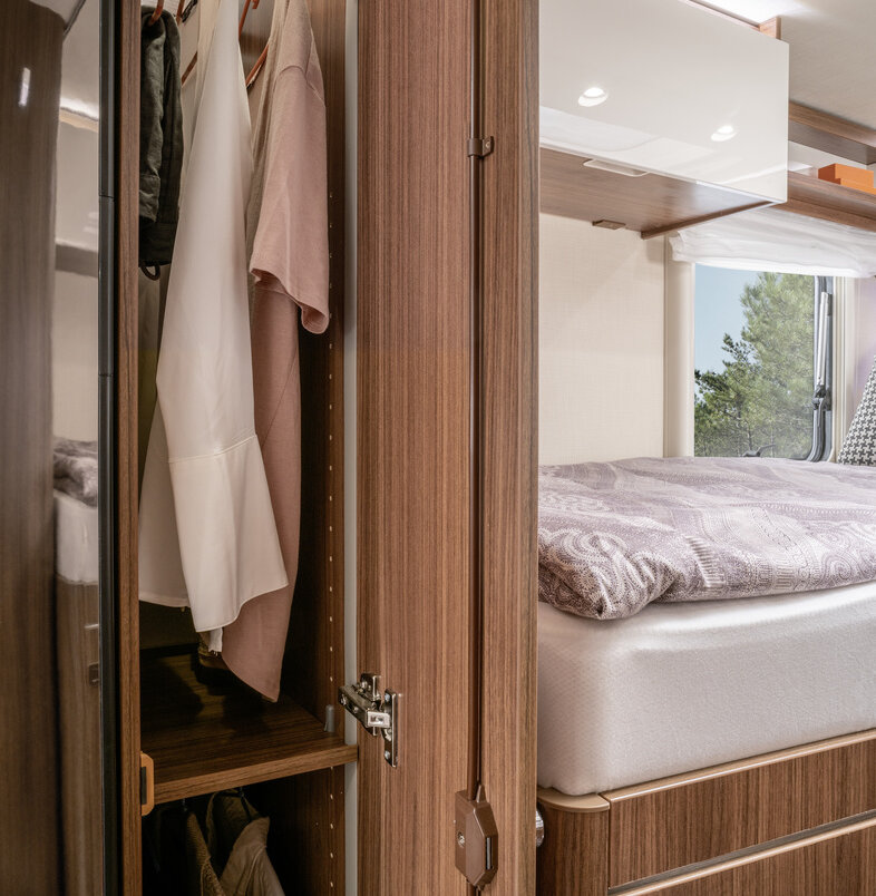 Opened, illuminated wardrobe with shirts on the clothes rail in the HYMER B ModernComfort