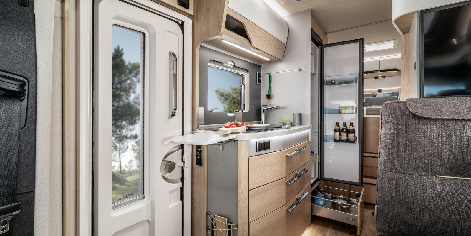 Küchenblock neben Eingangstüre, Arbeitsplattenerweiterung,, offener, voller Kühlschrank und Schublade im HYMER ModernComfort