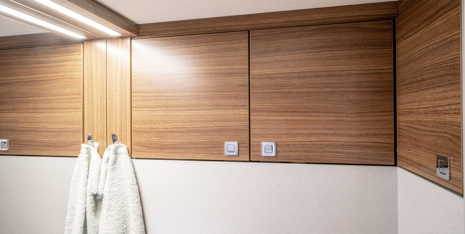 Front of the bathroom cabinets and towel hooks with two white towels in the bathroom of the HYMER B-Class ModernComfort