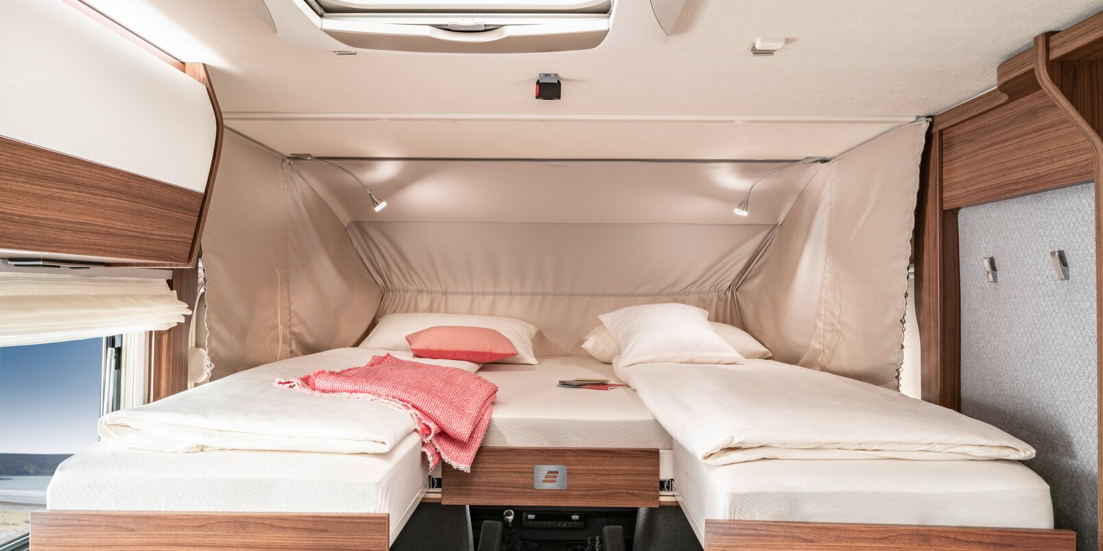 Lowered, covered fold-down bed with twin beds and decorative pillows in the HYMER B-MC I 680
