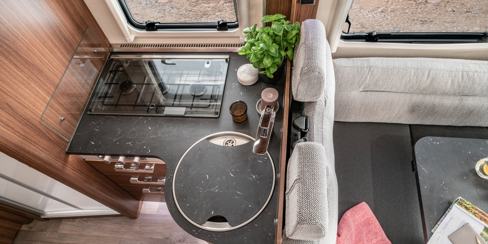Kitchen with 3-burner stove, sink with cover, rear wall with headrests of the seating area, towel in the HYMER ModernComfort