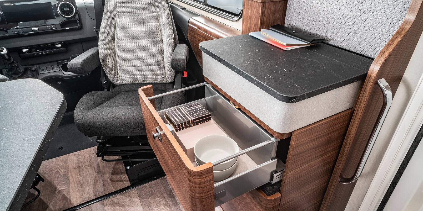 Opened, filled drawer on the sideboard between the entrance door and the passenger seat in the HYMER B ModernComfort