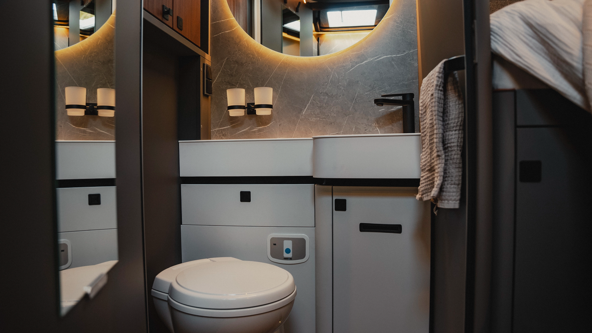 De stijlvolle badkamer biedt een moderne wasruimte, gekenmerkt door slim ontwerp en moderne apparatuur. Ervaar functionaliteit en elegantie in een kamer die perfect is afgestemd op reizen en een uitnodigende sfeer creëert.