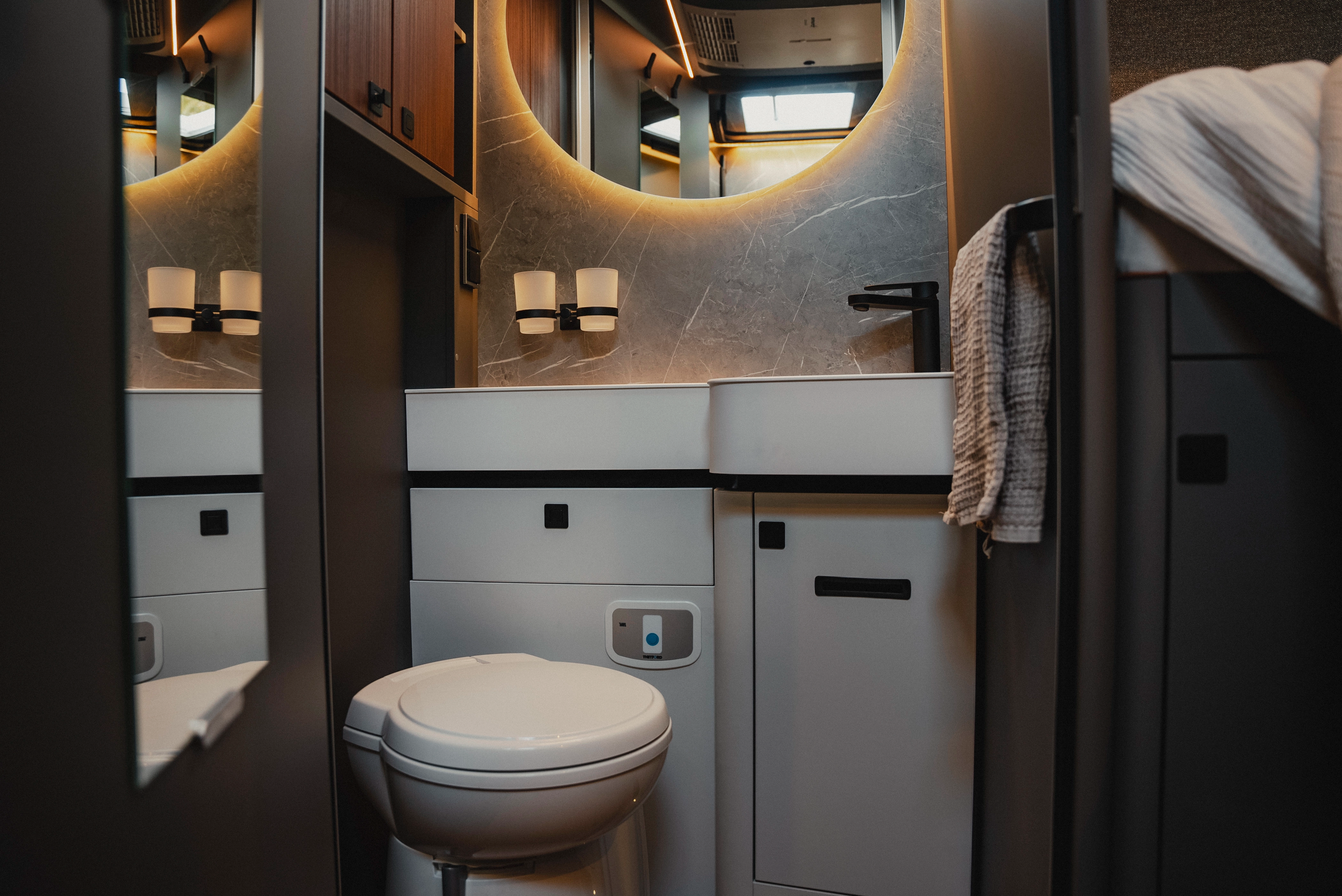 De stijlvolle badkamer biedt een moderne wasruimte, gekenmerkt door slim ontwerp en moderne apparatuur. Ervaar functionaliteit en elegantie in een kamer die perfect is afgestemd op reizen en een uitnodigende sfeer creëert.