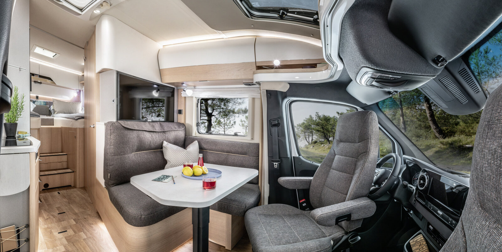Lounge seating group with driver's cab, set table, TV plasma and kitchen in the HYMER B ModernComfort T
