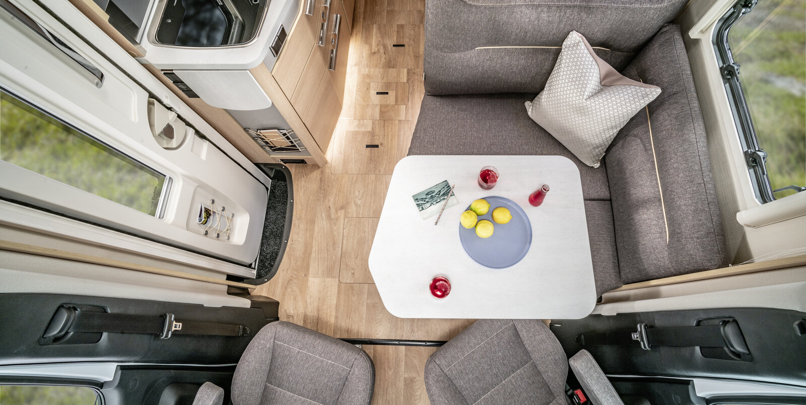 Wohnsitzgruppe mit Fahrersitzen, gedecktem Tisch, Eingangstüre und Küchenblock im HYMER Reisemobil B-MC T