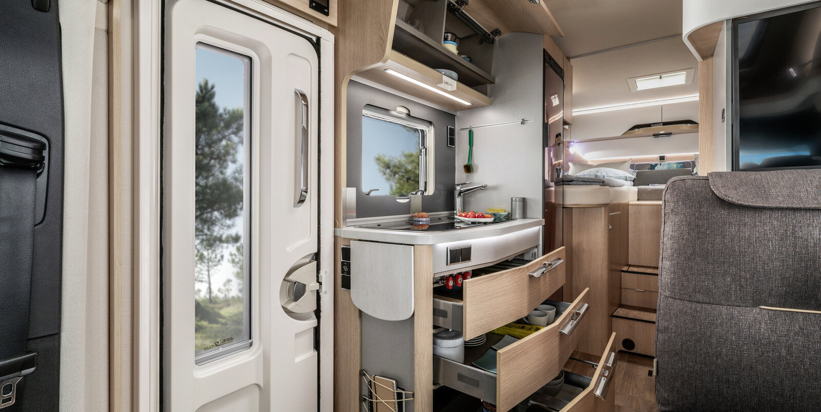 Opened drawers and overhead storage cupboards filled with kitchen utensils in the kitchen of the HYMER ModernComfort