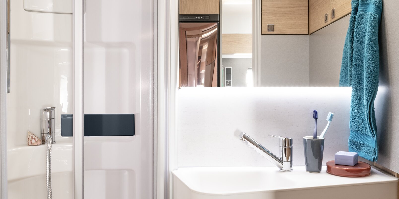 Komfortbad mit Duschkabine, Waschbecken, Spiegel, Toilette und Badutensilien im HYMER ModernComfort