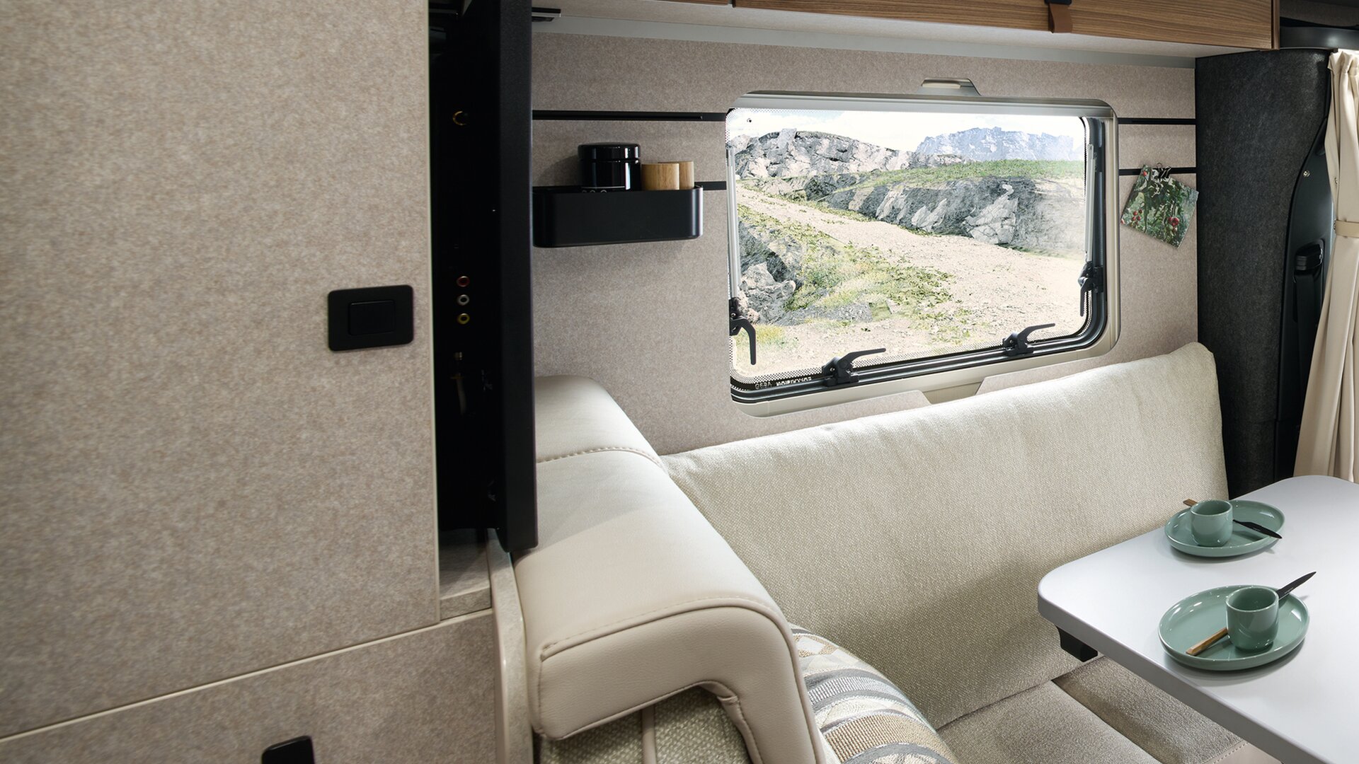 Der Fernseher in der Sitzecke des HYMER ML-T in der Stilwelt Velvet Ash schließt bündig mit der Wand ab. Zu sehen sind die modernen Nackenstützen.