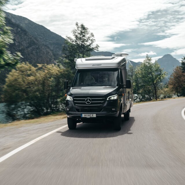 Der HYMER ML-T ist frontal zu sehen und fährt um eine Kurve. Die Umgebung ist aufgrund der Bewegung unscharf.