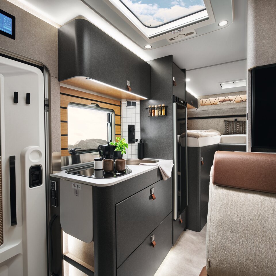 Auf dem Herd im HYMER ML-T in der Stilwelt Velvet Ash steht ein Topf. Davor ist im Anschnitt die Tür und darüber das HYYMER Connect Display zu sehen.