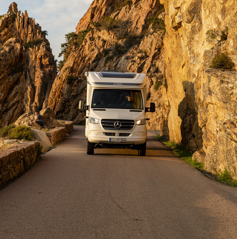 HYMER ML-T 570 driving downhill on a narrow road in an ocher-colored rock canyon