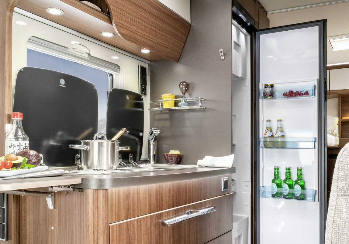 Kitchen block with worktop extension, saucepan on the stove, other kitchen accessories, open refrigerator in the HYMER ML-T