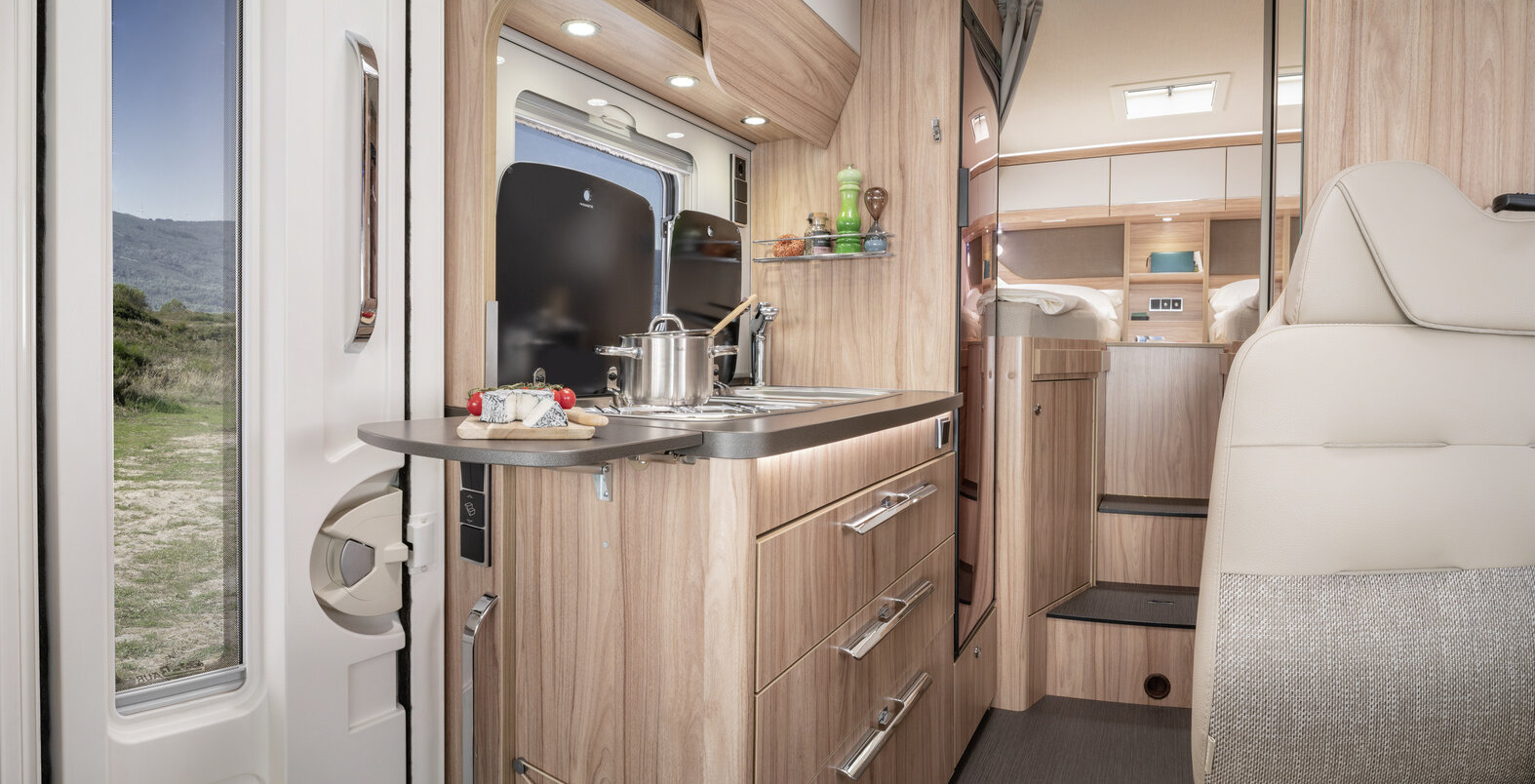 Interior in the HYMER ML-T 570: entrance door, kitchen block with worktop extension, rear bench seating area, sleeping area