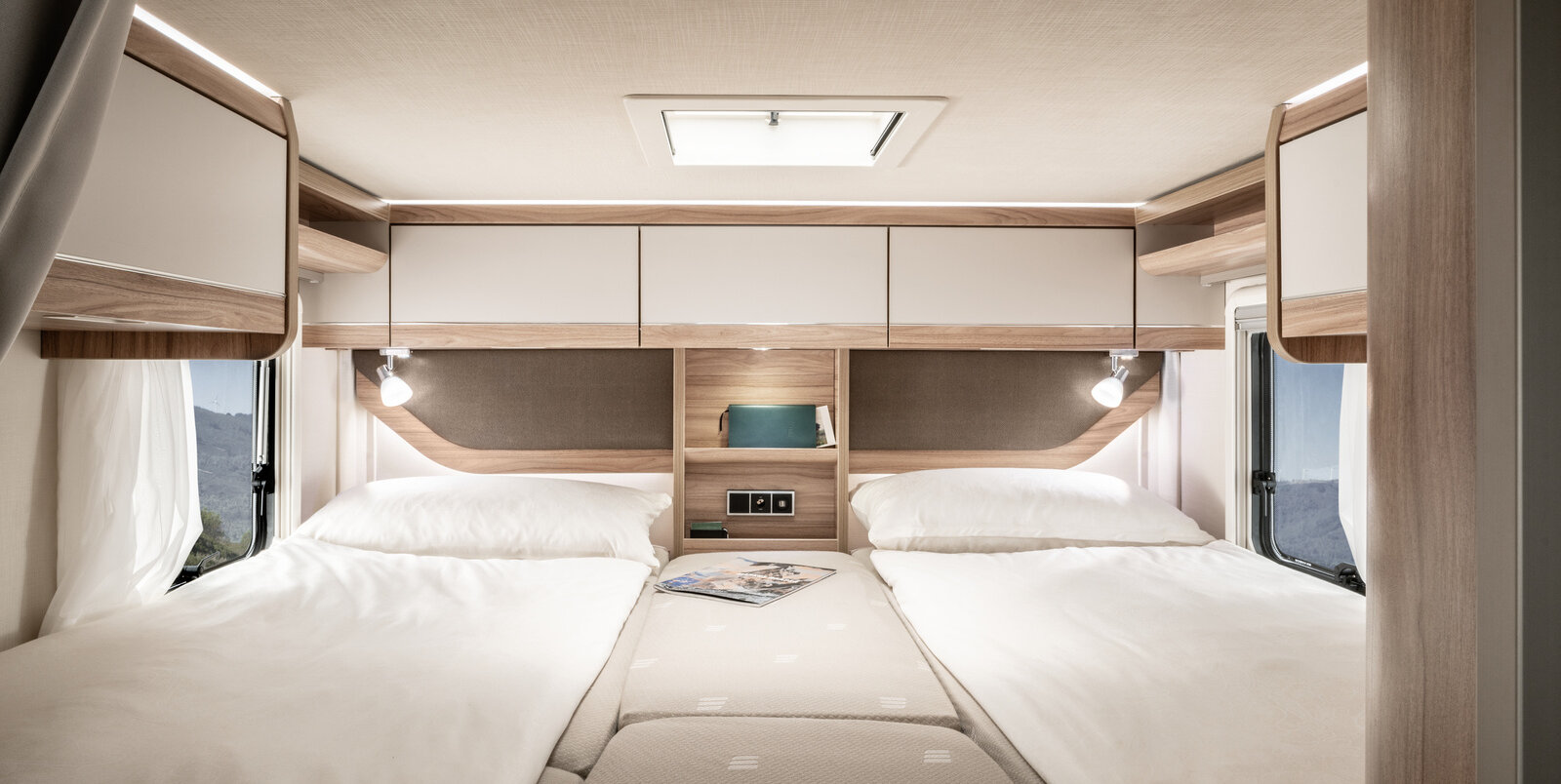 Covered lengthways single beds, central additional cushions, overhead storage cupboards, storage board, reading lights in the bedroom of the HYMER ML-T