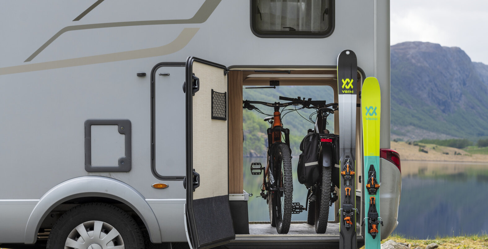 Rear garage, open on both sides, loaded with two mountain bikes and two snowboards leaning against it on the Hymermobil ML-T 580