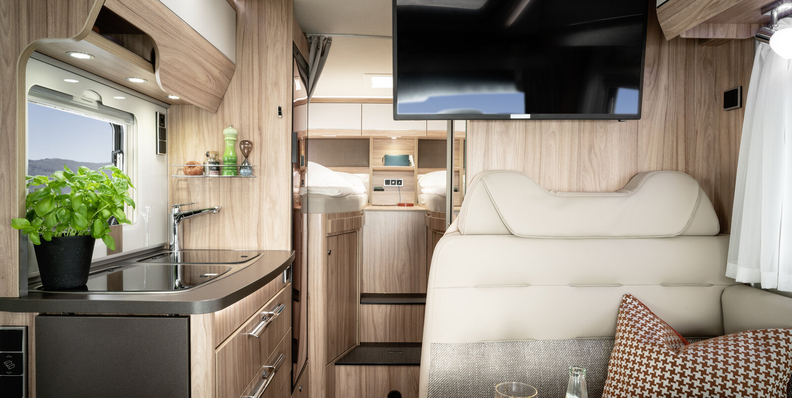 Table and back seat of the seating group, TV plasma, kitchen block with utensils and sleeping area in the HYMER ML-T 570