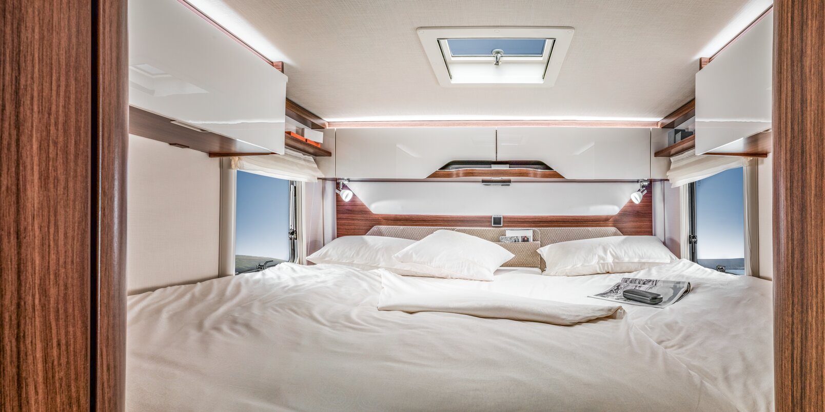 Rear bed covered with white bed linen in the HYMER B ModernComfort WhiteLine motorhome