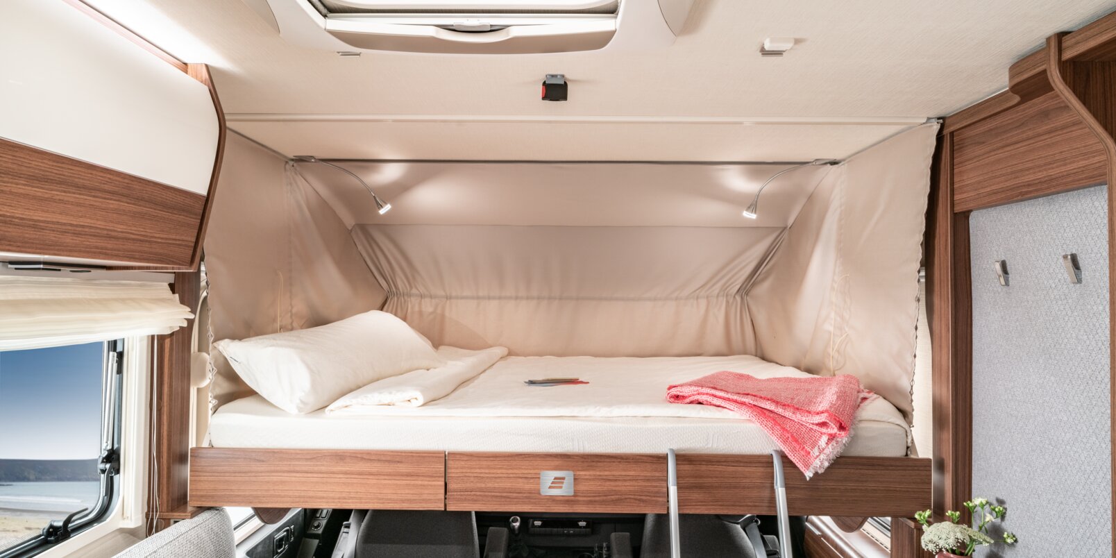 Lowered, covered fold-down bed, pink blanket and access ladder in the HYMER B -MC I WhiteLine