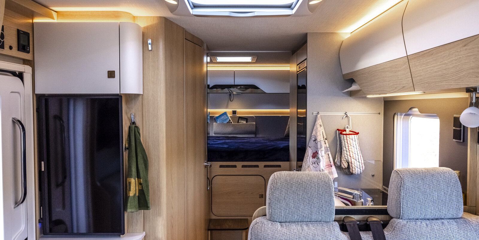 Living area in the HYMER B-MC-T WL: backrest seating area with headrests, kitchen block, refrigerator, view of the rear area