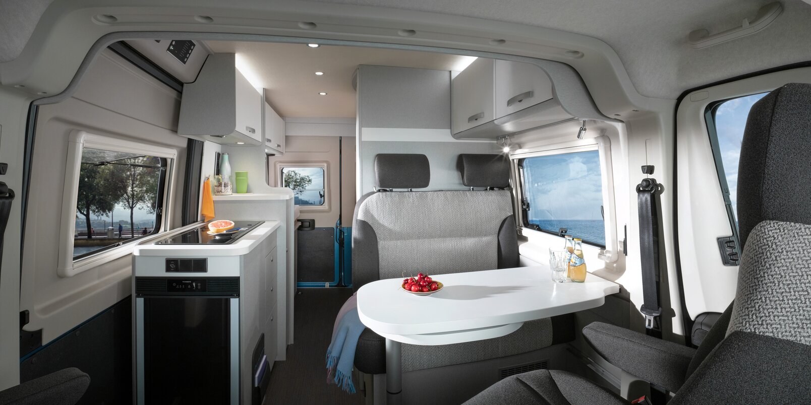Interior in the HYMER Free 540 Blue Evolution: seating area with table, entrance door, kitchen block, rear area