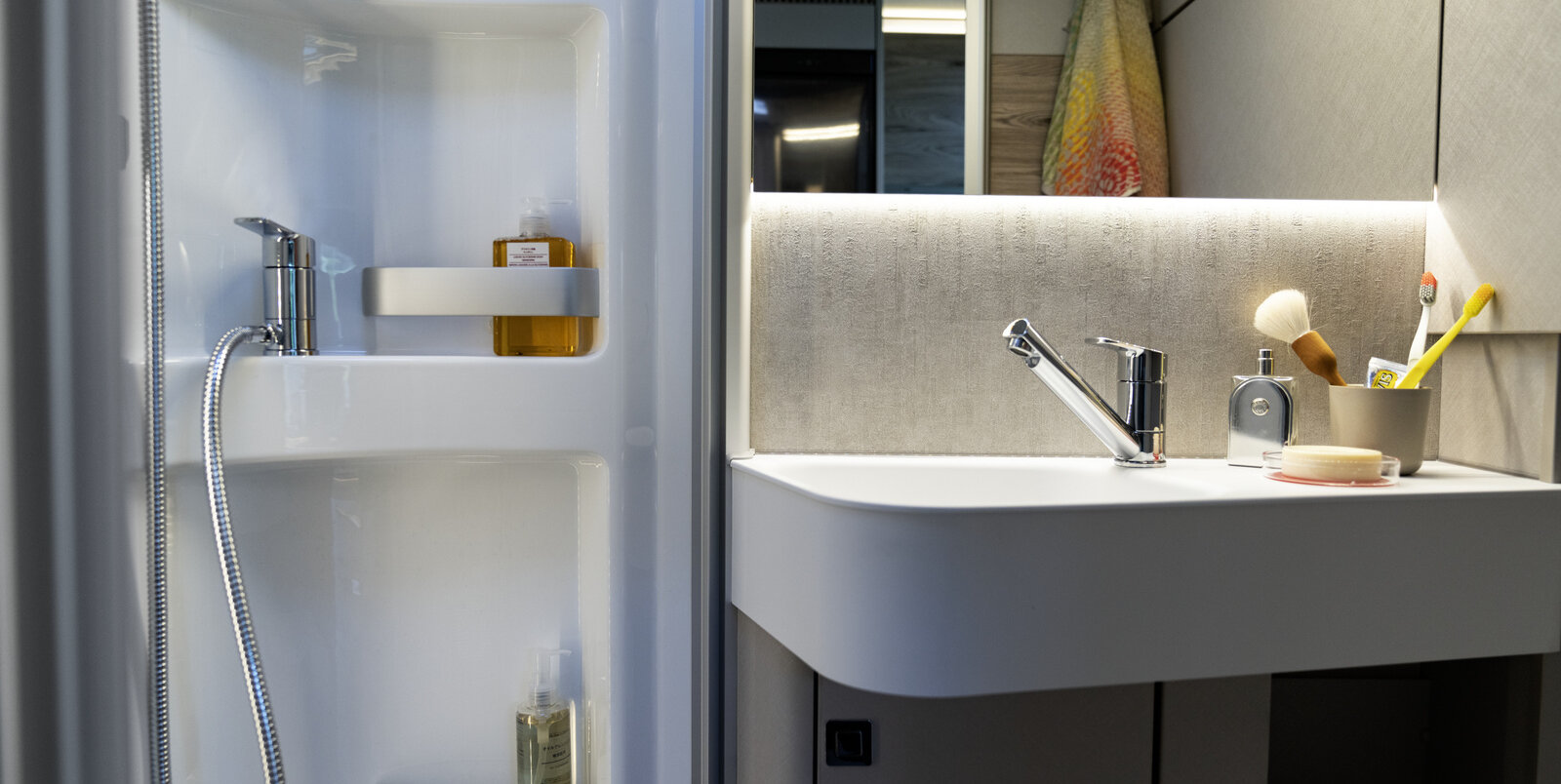 Wastafel met tandenborstelbeker, spiegel, badkamermeubels en plank in de douchecabine van de HYMER Exsis-i 580 Pure