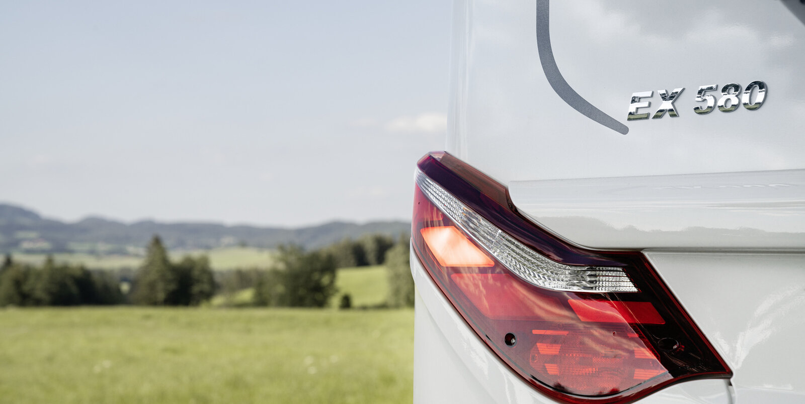 The rear light of the HYMER Exsis-t 580 Pure on a Citroën with a green meadow and trees in the background