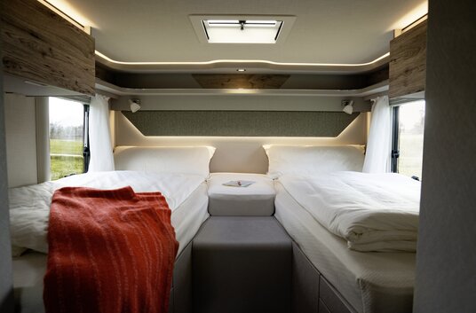 Covered lengthways single beds and red blanket in the rear of the HYMER Exsis 580 Pure