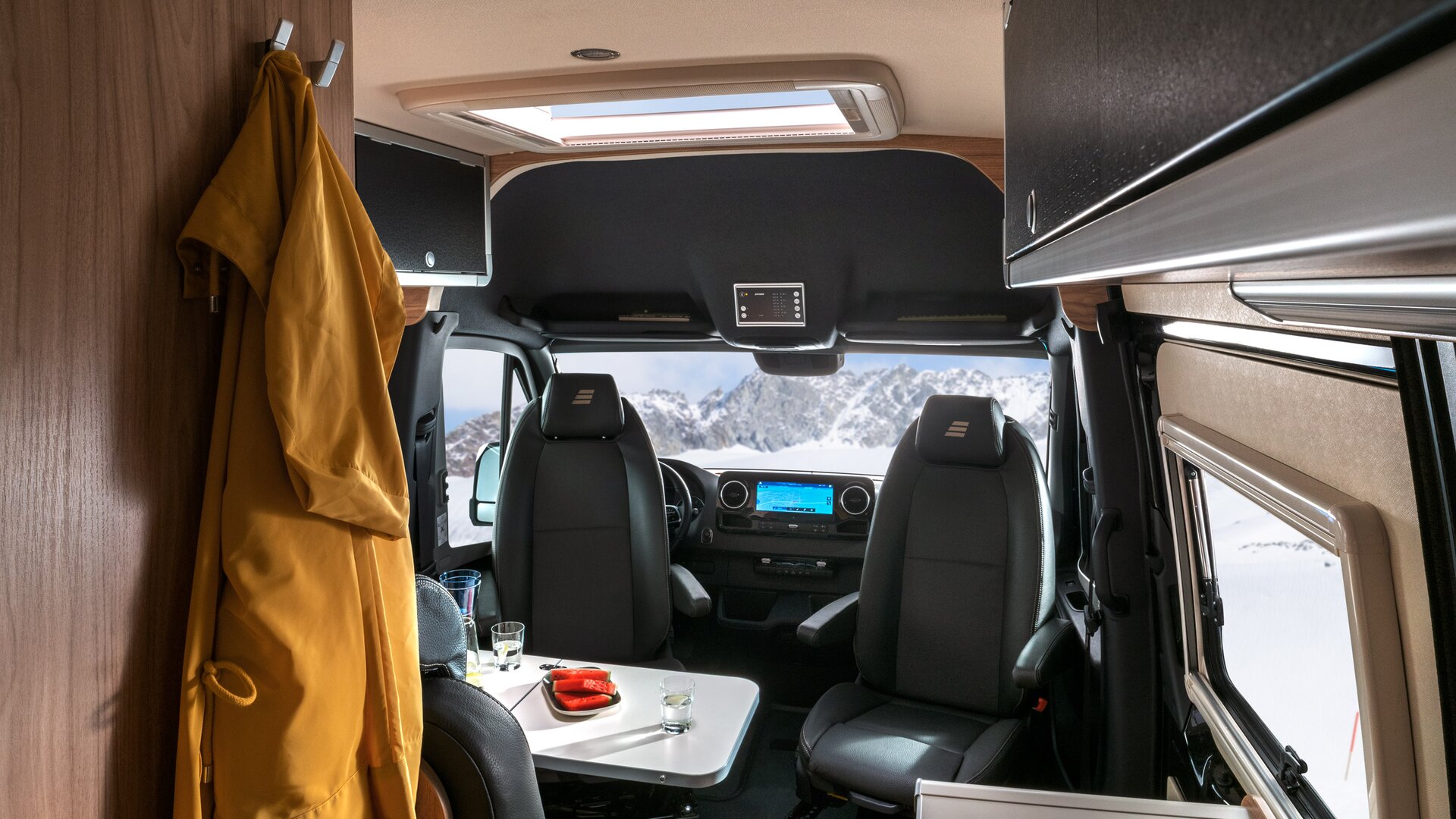 Interior in the HYMER Grand Canyon S CrossOver: yellow bathrobe on hooks, seating area with occupied table, driver's area