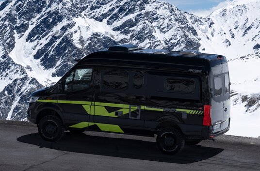 Mercedes Sprinter based HYMER Grand Canyon S CrossOver driving on the road in the snowy mountains
