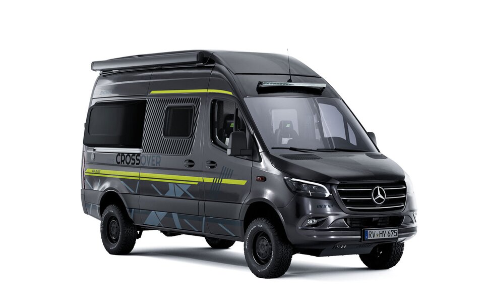 Schräge Seitenansicht eines dunklen Camper Vans mit seitlicher Beklebung in der Farbe Neongrün, dunkle Reifen mit schwarzen Felgen sowie eine schwarze Markiese, Vorne über der Frontscheibe ist eine LED-Lightbar angebracht
