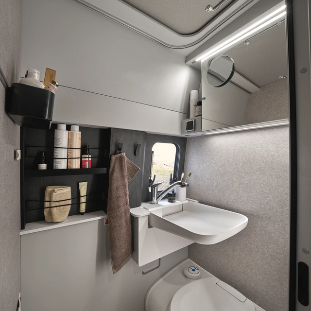 Dans la salle de bains compacte du HYMER Grand Canyon S dans le monde du style Pearl Grey, il existe de nombreuses options de rangement pour vos articles de toilette.