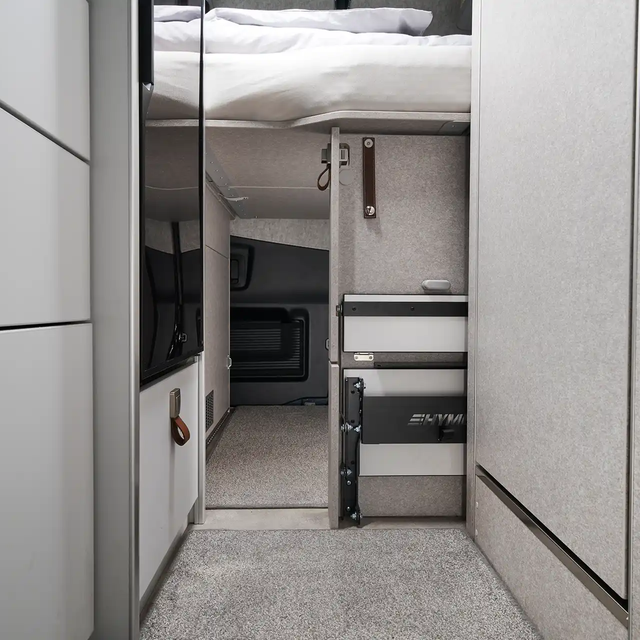 On peut voir que la garage arrière du HYMER Grand Canyon S dans le monde du style Pearl Grey est accessible depuis l'intérieur du véhicule sous le lit.