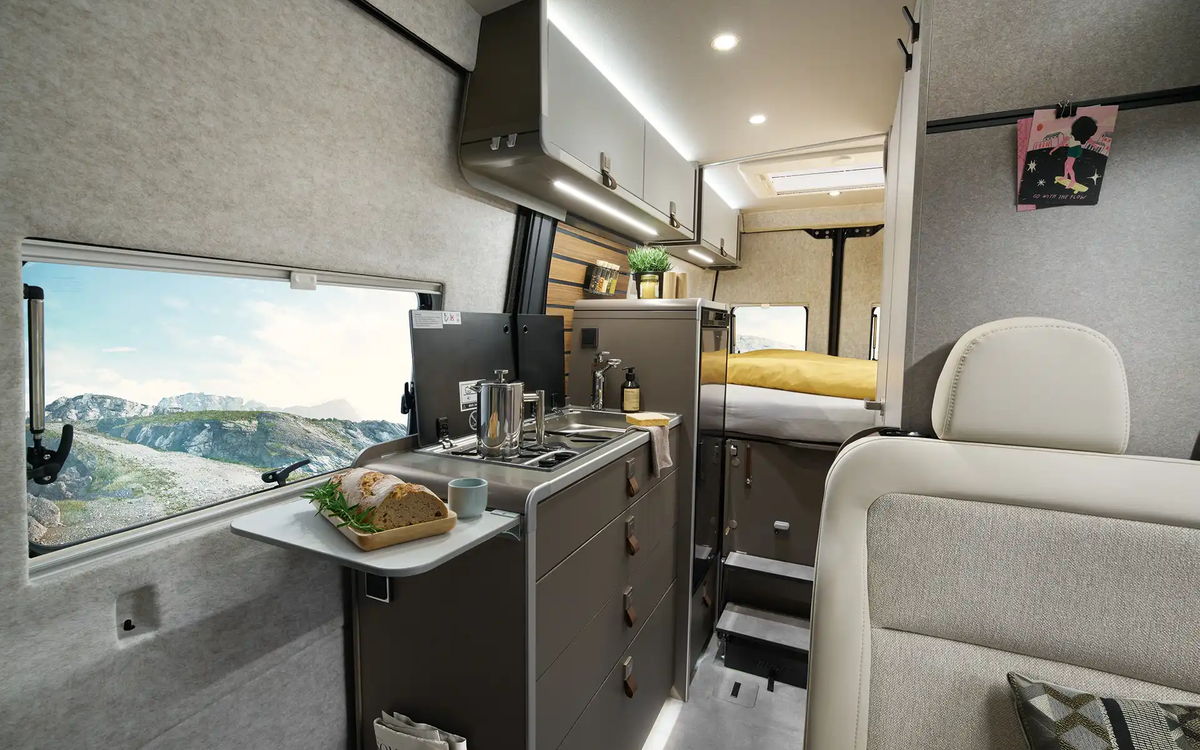 Sur l'extension de la cuisine du HYMER Grand Canyon S, il y a du pain. En arrière-plan, la kitchenette avec cuisinière, évier et réfrigérateur est visible.