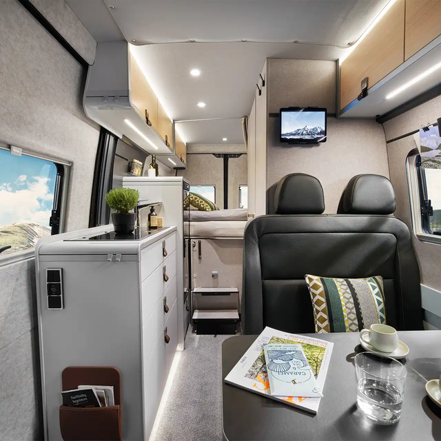La vue à travers l'intérieur du HYMER Grand Canyon dans le monde du style Pearl Grey, de la zone de sièges à la zone de couchage.