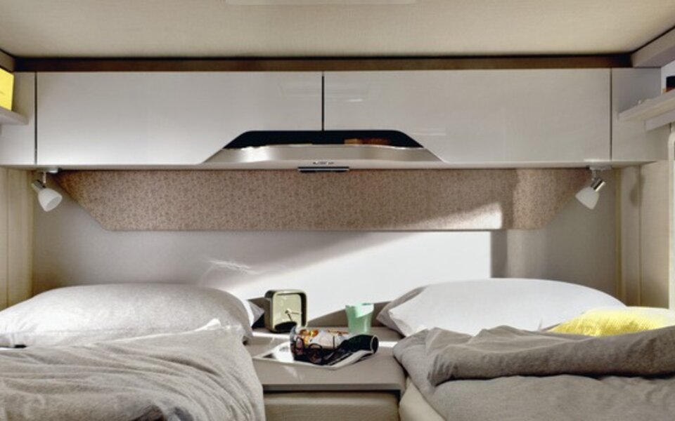 Sleeping area in the HYMER T-Class S 680: two made-up lengthways single beds, yellow bath towel, central access, overhead storage cupboards