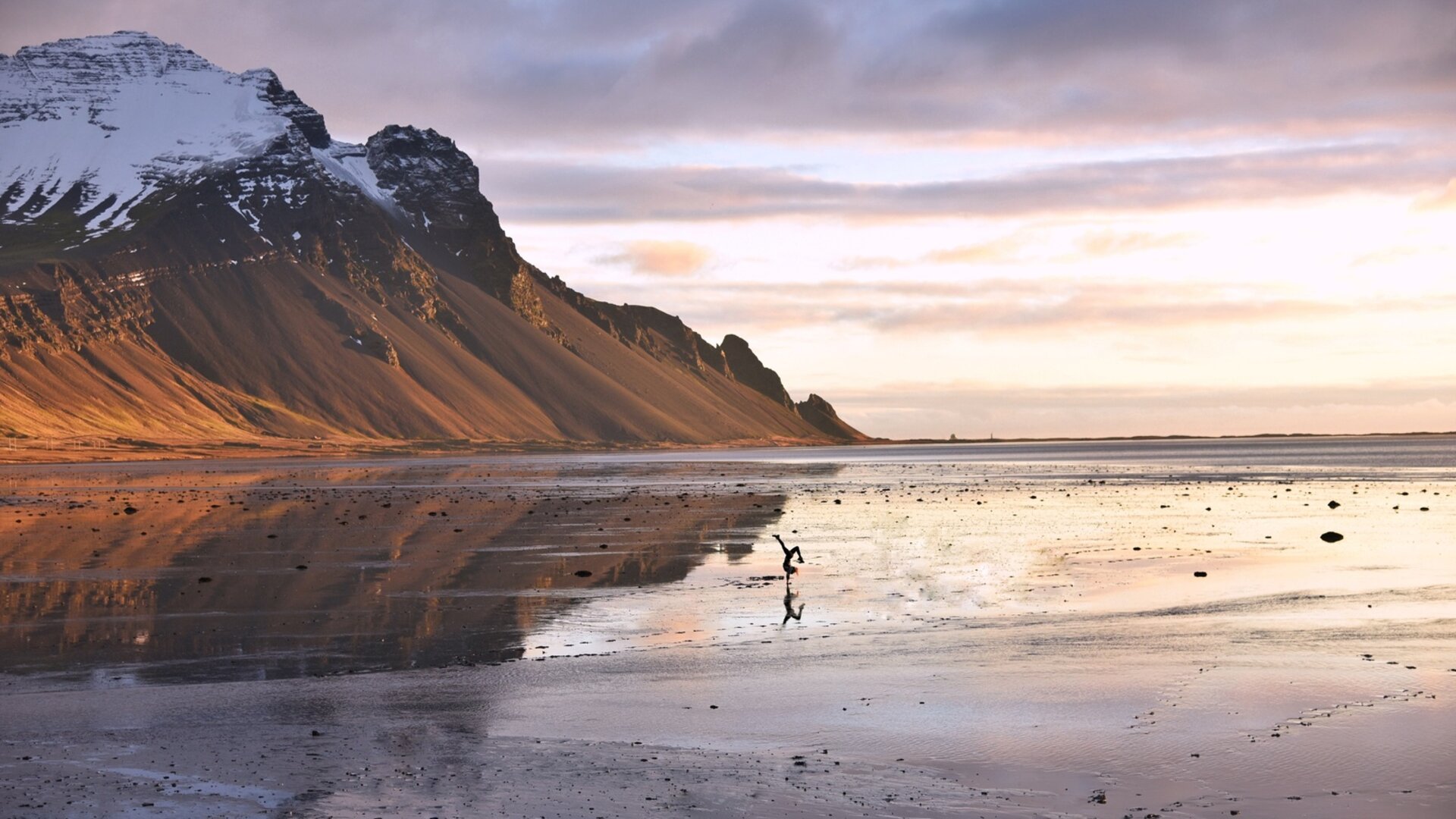 Ett landskap speglas i en våt yta, det finns snötäckta berg att se. Från reseberättelsen "Med husbil till Island".