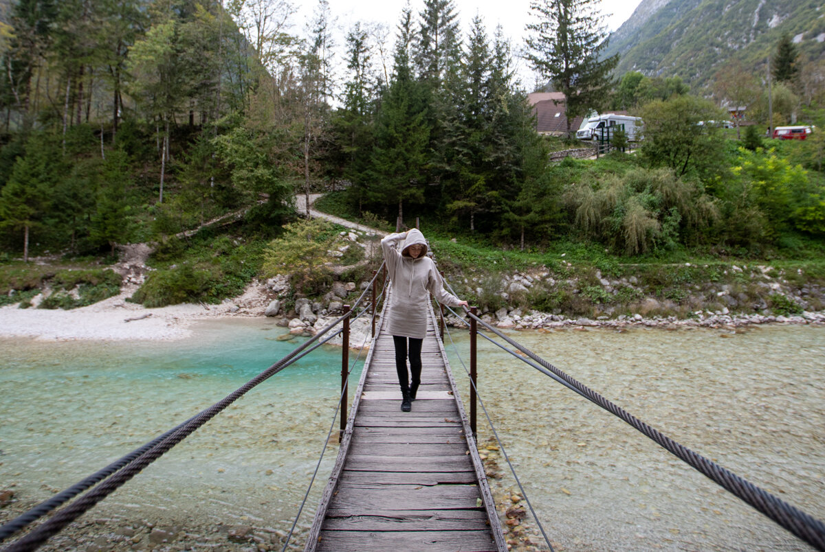 Vrouw passeert rivier Soča via de hangbrug / Camper op de achtergrond