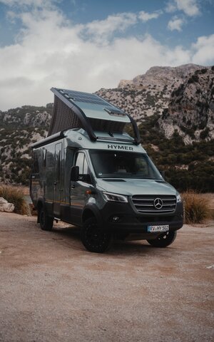 View from the front side of the Venture S, with the pop-top extended, mountains in the background.
